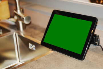 Tablet with green screen near the kitchen faucet