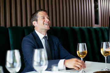 Handsome businessman dressed in the suit drinking wine. Businessman and businesswoman enjoying in the restaurant.