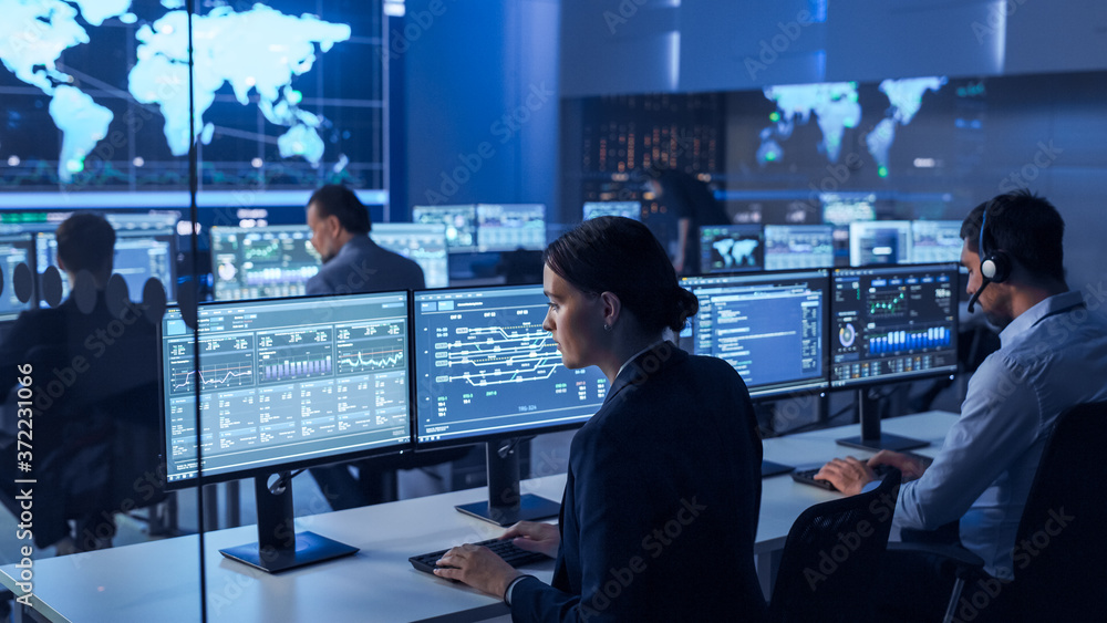 Poster Team of Professional Computer Data Science Engineers Work on Desktops with Screens Showing Charts, Graphs, Infographics, Technical Business Data and Statistics. Dark Control and Monitoring Room.