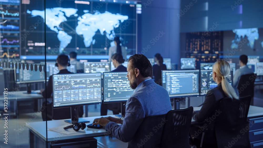 Poster Team of Professional Computer Data Science Engineers Work on Desktops with Screens Showing Charts, Graphs, Infographics, Technical Neural Data and Statistics. Low Key Control and Monitoring Room.