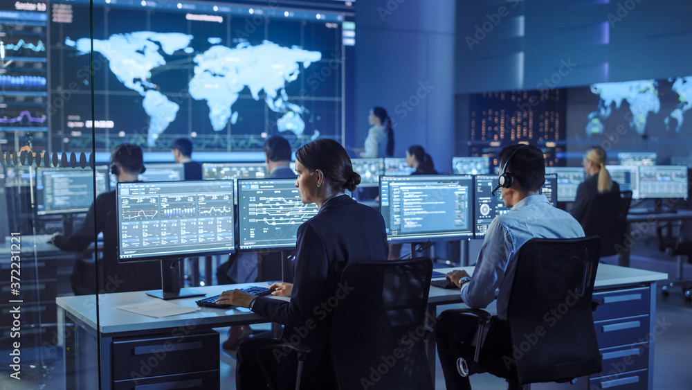 Poster Team of Professional Computer Data Science Engineers Work on Desktops with Screens Showing Charts, Graphs, Infographics, Technical Neural Data and Statistics. Low Key Control and Monitoring Room.