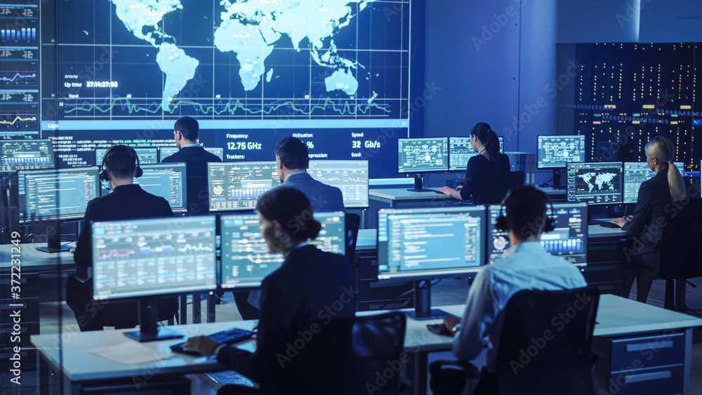 Poster Team of Professional Computer Data Science Engineers Work on Desktops with Screens Showing Charts, Graphs, Infographics, Technical Neural Data and Statistics. Low Key Control and Monitoring Room.