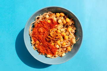 Famous traditional Arabic, Egyptian dish - Koshari. National Kushari in a turquoise plate on blue background. Top view.
