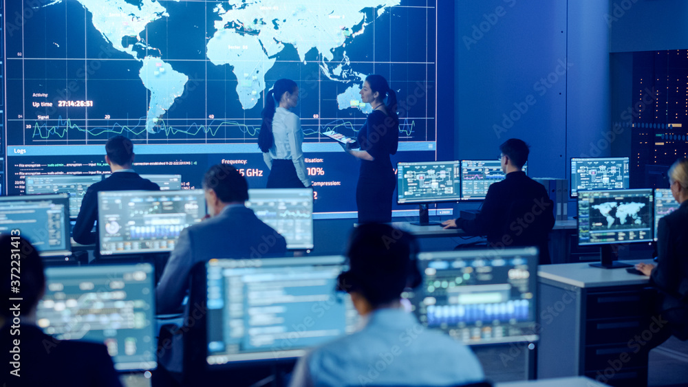 Leinwandbilder Project Manager and Computer Science Engineer Talking while Using Big Screen Display Showing Global Map and Data. Telecommunications Company System Control and Monitoring Room.