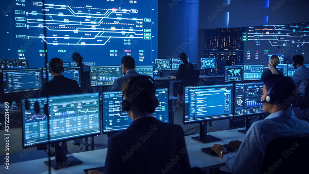 Poster Team of Professional Computer Data Science Engineers Work on Desktops with Screens Showing Charts, Graphs, Infographics, Technical Neural Data and Statistics. Low Key Control and Monitoring Room.