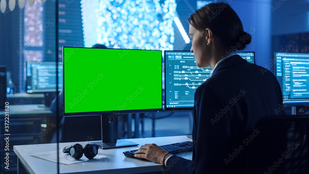 Poster Confident Female Data Scientist Works on Personal Computer with Green Screen Mock Up in Big Infrastructure Control and Monitoring Room with Neural Network. Woman Engineer in an Office with Colleagues.