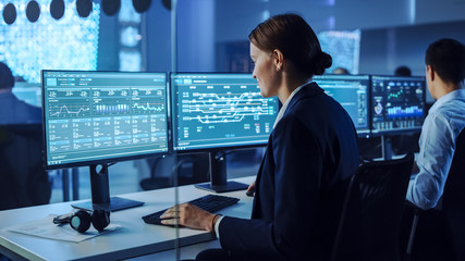 Confident Female Data Scientist Works Closely to her Young Colleague in Big Control and Monitoring...