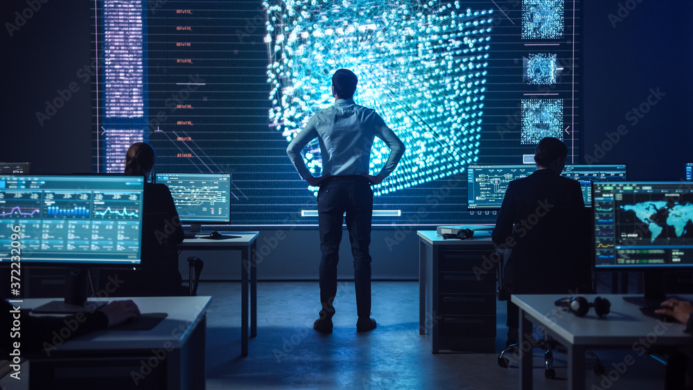 Poster Project manager Stands Next to Big Screen with Neural Network. Team of Professional Computer Data Science Engineers Work on Desktops in a Dark System Control and Monitoring Telecommunications Office.