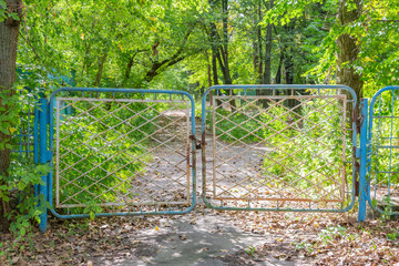 Old crooked gate closed on a large rusty padlock with chains