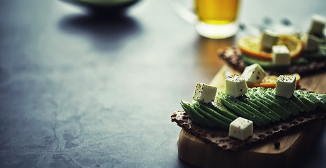 Avocado cooking recipes. Ripe green avocado on a wooden cutting board for serving.