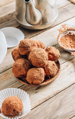 Homemade chocolate truffles candy ball on a plate sprinkled with cocoa on a rustc wooden background.