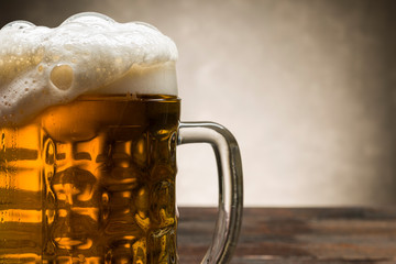 close up of beer pint with foam on rustic background