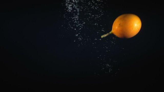 Falling granadilla in the water on black background