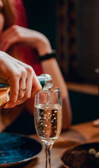 hand with bottle wine or champagne pouring in wine glass.