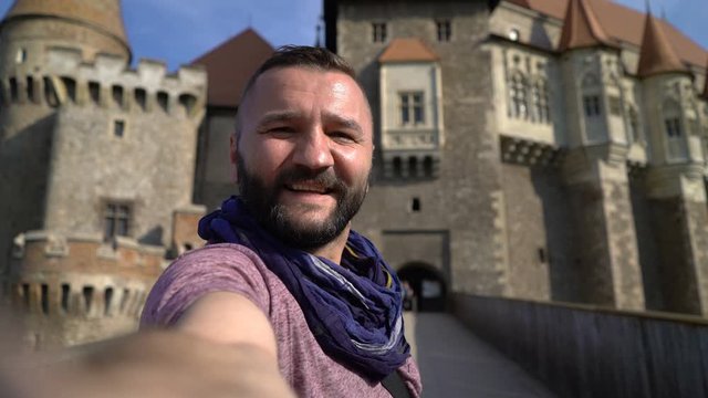 Tourist taking selfie photo, video by Corvin Castle in Romania