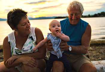 Fototapeta premium The grandparents playing with their baby granddaughter on the beach