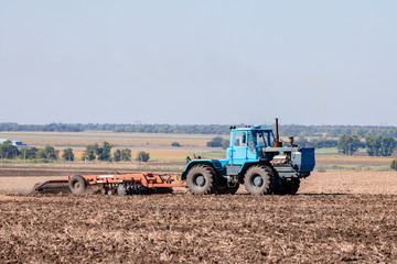 An old tractor works in the field. Agricultural work.