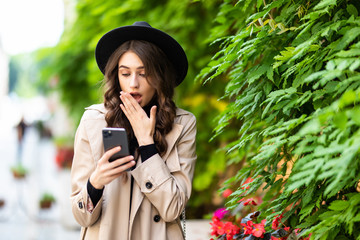 Shocked woman finding surprising news on phone in the street