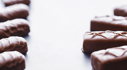 Chocolate bars on a black background in backlight. Chocolate with filling. Sweet sweets for snack and tea.