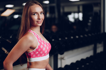 Fototapeta na wymiar Portrait of a young woman in sportswear posing in a gym