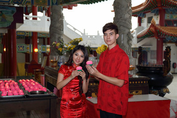 Young south east asian Chinese man woman traditional costume cheongsam praying outdoors at temple