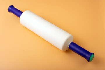 Top view of a multicolored plastic rolling pin on an orange background