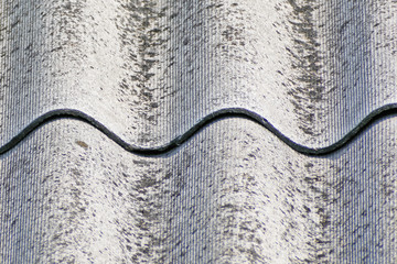 Roof texture. A fragment of an old roof made of wave slate sheets in close-up.