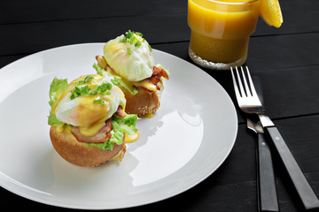 Top view of toasted buns with bacon, lettuce and poached egg
