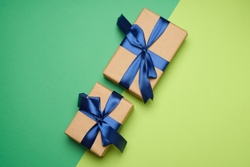two rectangular boxes wrapped in brown paper and tied with a silk ribbon with a bow