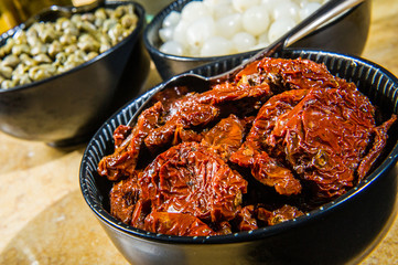 Italian sun dried tomatoes with garlic, bright wooden table background