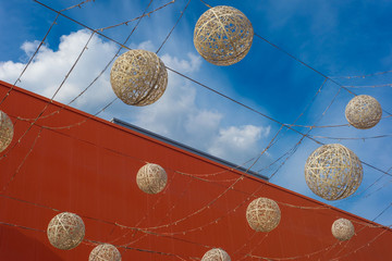 decoration of round balls of lamps, against the background of a blue sky with clouds, against the background of a cut of the building of a red hypermarket. Freedom texture, balloons in the sky