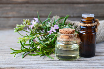 Rosemary essential oil in a glass bottles with fresh green rosemary herb on old wooden table for spa,aromatherapy and bodycare.Copy space.