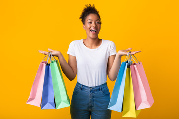 Portrait of cheerful black lady holding shopping bags