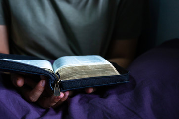 woman praying on the bed in the morning, book or holy bible opening in front of person bow down head and hand praying, Christian concept, praying for world crisis,