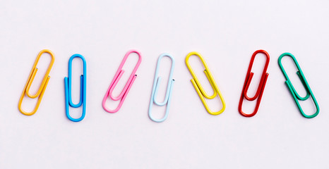 Colorful pastel paper clips isolated over white background. Red, pink, yellow, blue and green plastic paperclips.