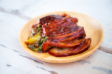 Chinese lacquered pork slices with its caramelized sauce prepared for eating in a wooden plate