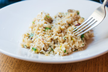 Delicious Italian vegetarian risotto cooked with mushrooms and onions served in white plate.