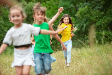 Carefree. Kids, children running on green forest. Cheerful and happy boys and girs playing, laughting, running through green blooming meadow. Childhood and summertime, sincere emotions concept.