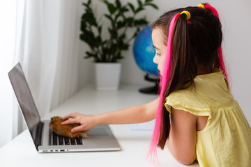 Cheerful young little girl with a pet hamster using laptop computer studying through online...