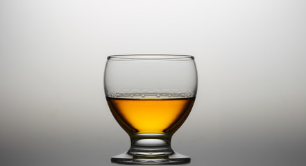 Glass of cognac or whiskey over gradients light background.