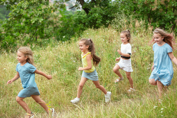 Naklejka na ściany i meble Angels. Kids, children running on green forest. Cheerful and happy boys and girs playing, laughting, running through green blooming meadow. Childhood and summertime, sincere emotions concept.