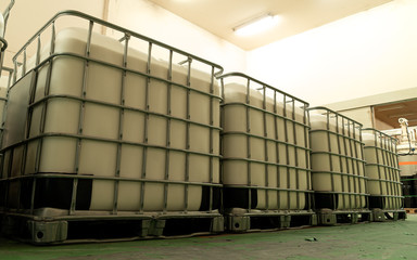 Look up view and low light inside of the factory. The large white tanks in cage of chemical...