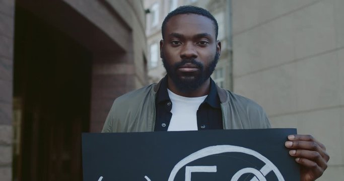 Crop view of male african american activist holding placard with no 5g sign. Young man on single protest against new technology and compatible antenna deployment at city street