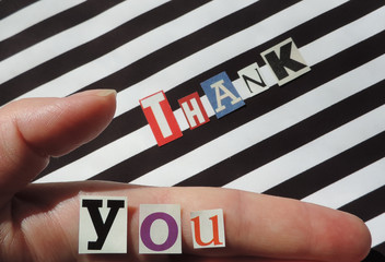 thank you words made from paper letters cut from magazines on a striped black and white surface . Selective Focus      