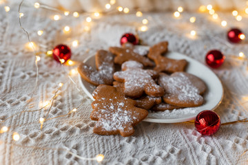 Christmas or New Year's gingerbread on a bed with a white blanket and a festive light garland. Red Christmas toys. Selective focus