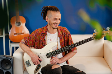 Obraz premium Young man guitar player sitting and performing on a couch