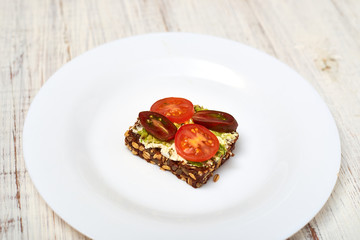Slice of cereal bread with cream cheese, avocado and vegetables. Vegetarian sandwich.
