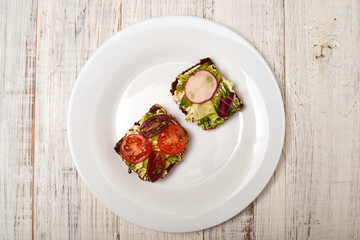 Slice of cereal bread with cream cheese, avocado and vegetables. Vegetarian sandwich.