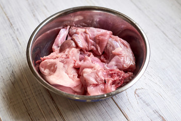 Raw rabbit in a bowl. Cutting meat, preparing for cooking.