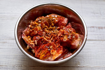 Raw rabbit in a bowl with spices. Marinate meat, preparing for cooking.